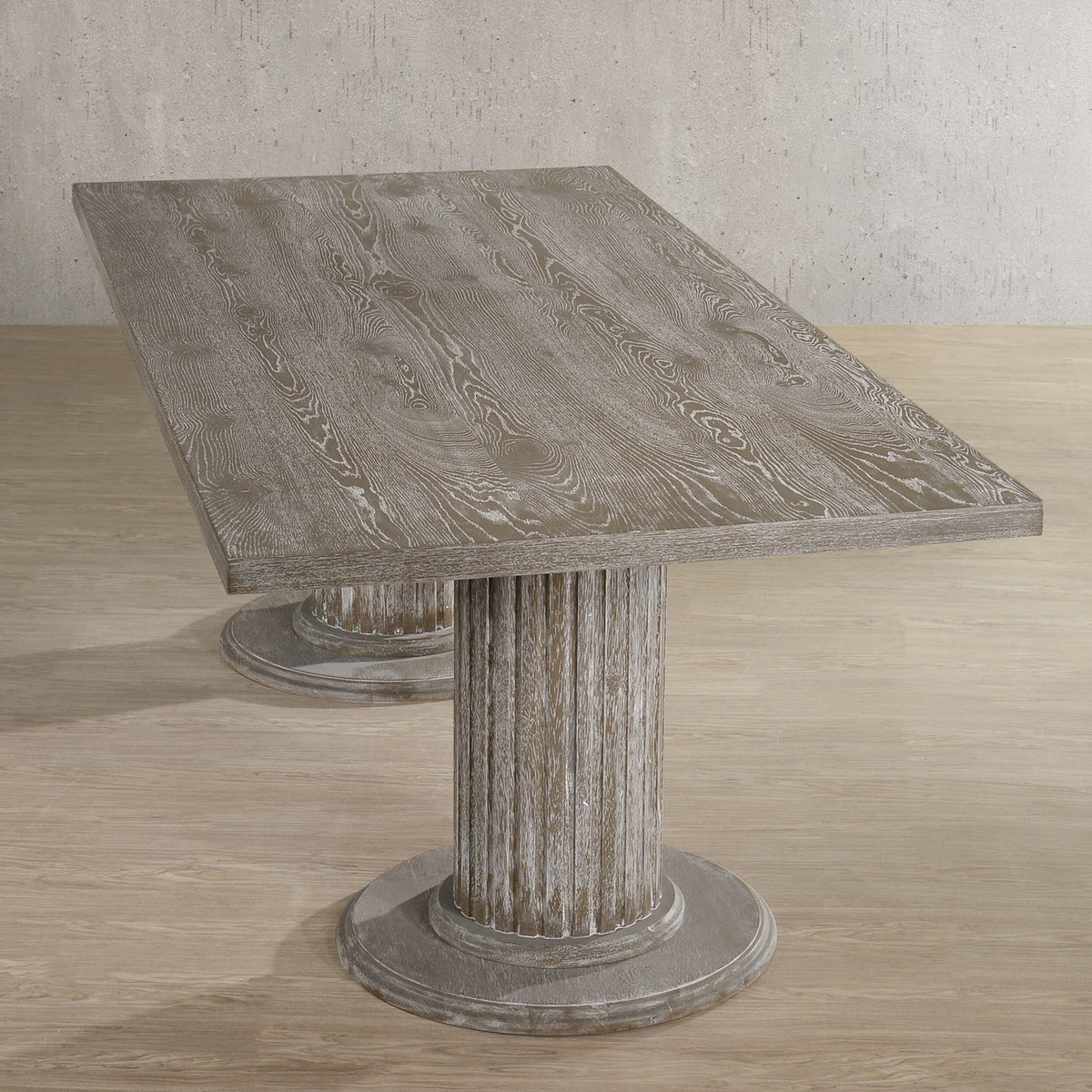 Reclaimed wood dining table with slanted top and round pedestal base, beige-gray finish.
