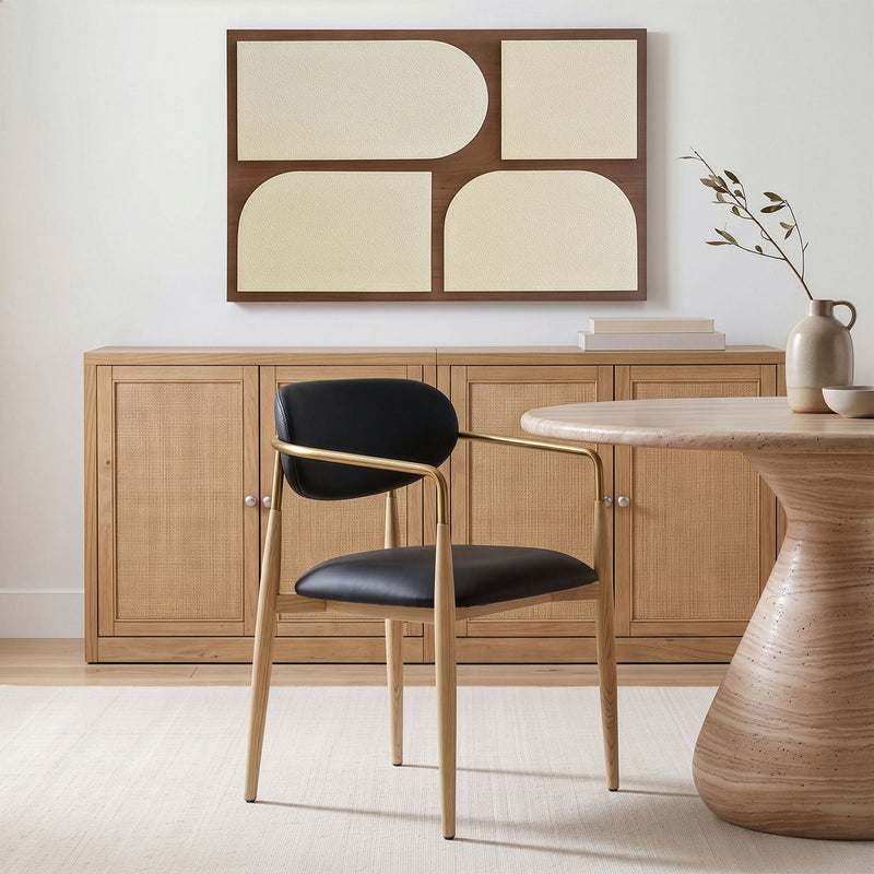 Vegan leather dining arm chair with black seat and rounded back, gold-tone arms, wood legs