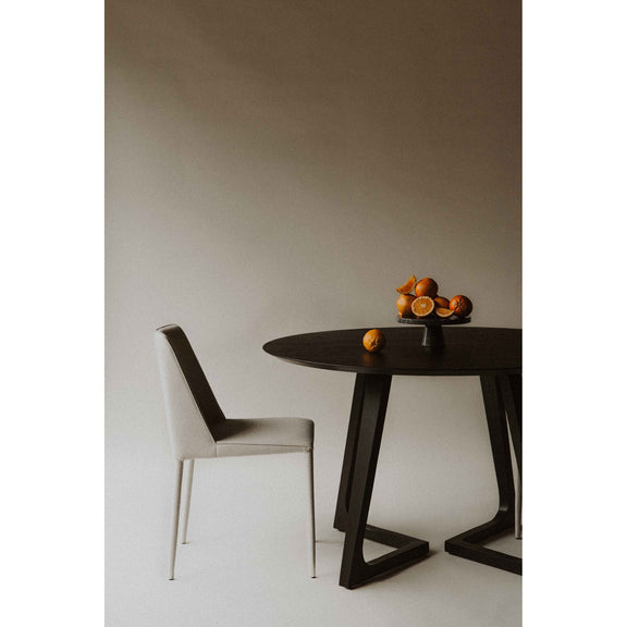 Round dining table with dark round top and angled pedestal base