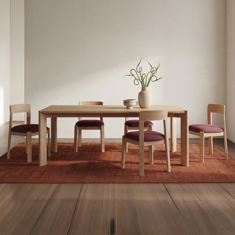 Berry purple upholstered dining chairs with light wood frames, styled around a table