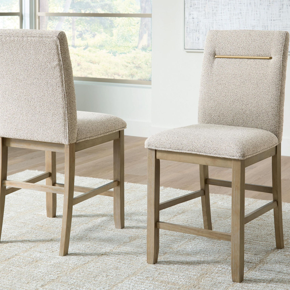Upholstered barstool set of 2 with beige seats, light brown legs, and gold accent bar
