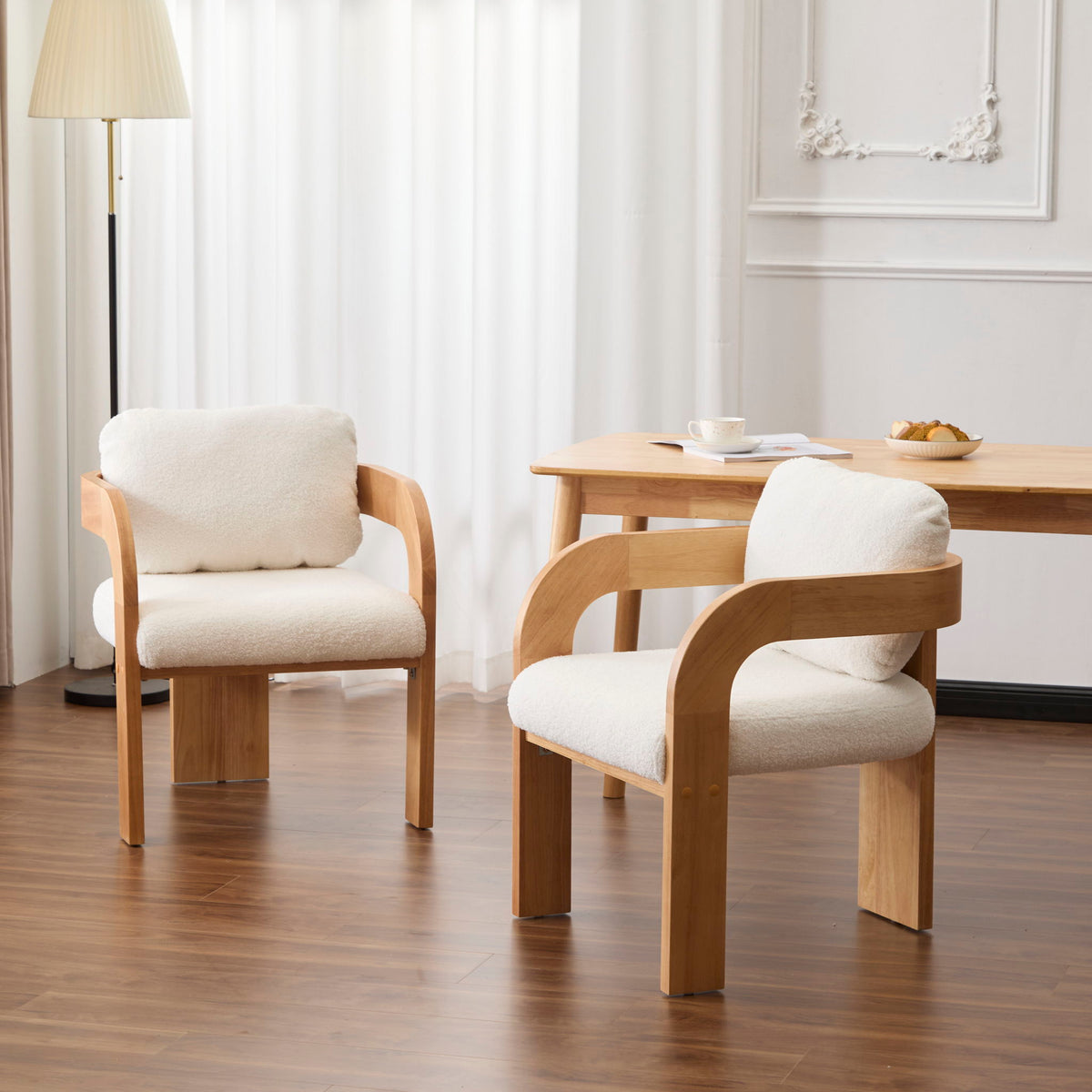 Two dining chairs with cream upholstery, pillow backs, and curved wooden frames
