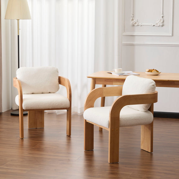 Two dining chairs with cream upholstery, pillow backs, and curved wooden frames