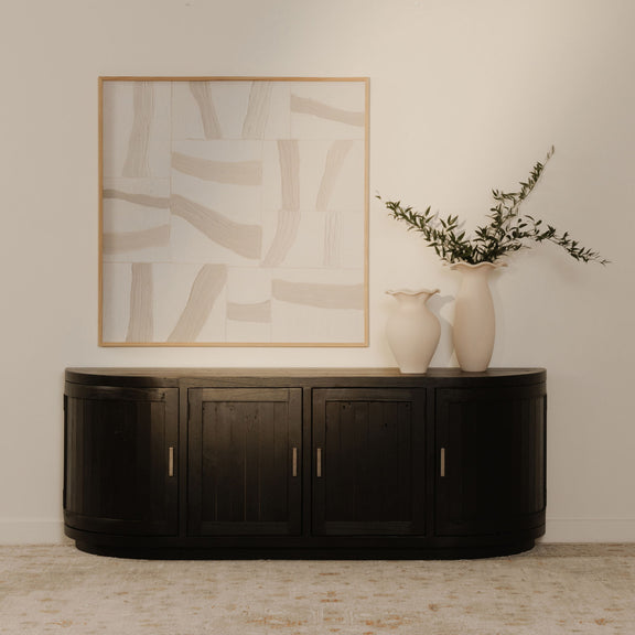 Black round media cabinet with four door fronts and vertical gold-tone handles