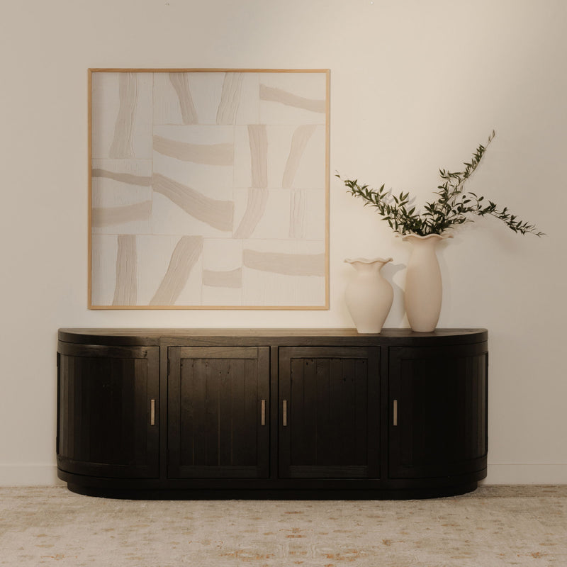 Black round media cabinet with four door fronts and vertical gold-tone handles