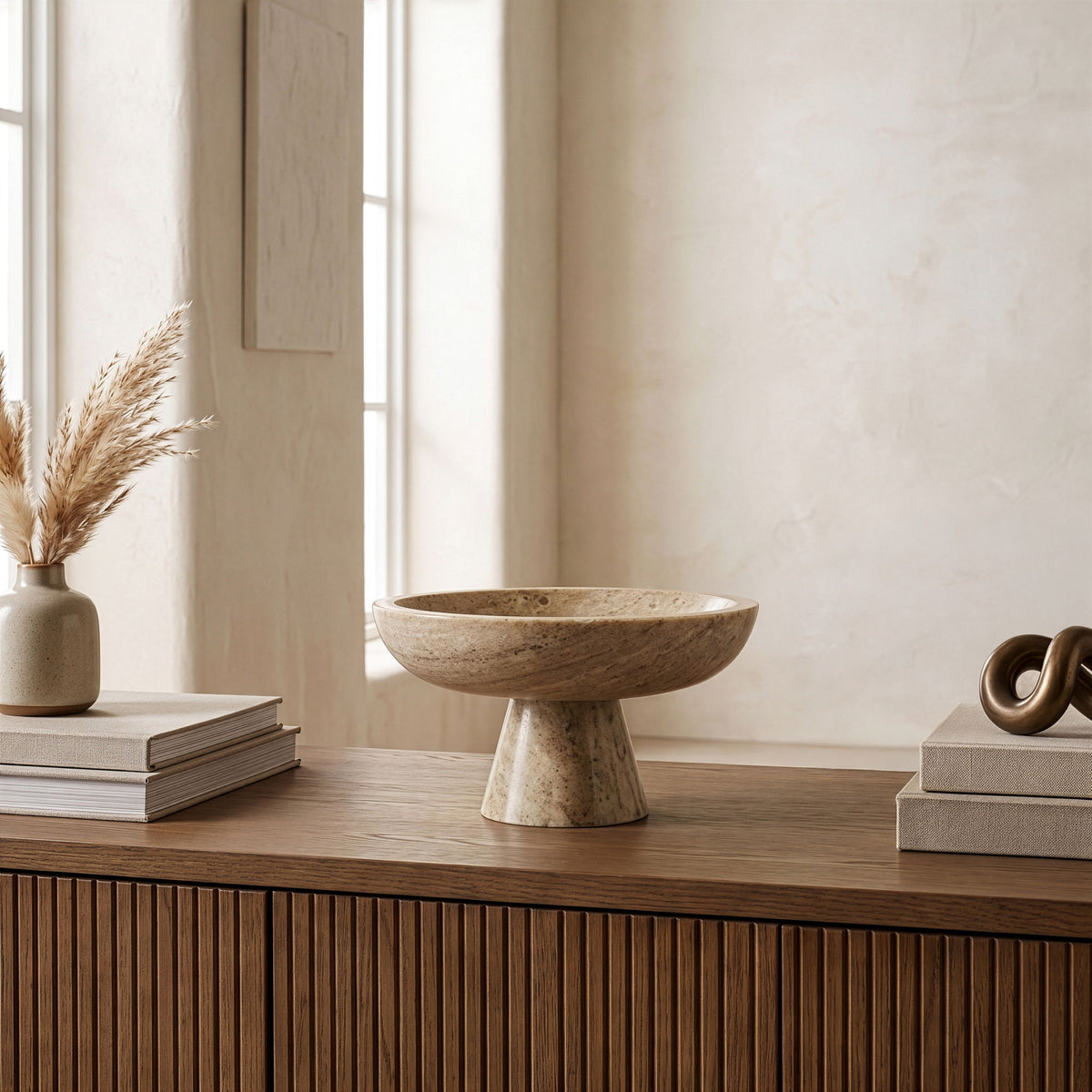 Beige marble pedestal bowl with shallow round basin and speckled stone texture