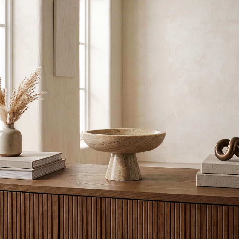 Beige marble pedestal bowl with shallow round basin and speckled stone texture
