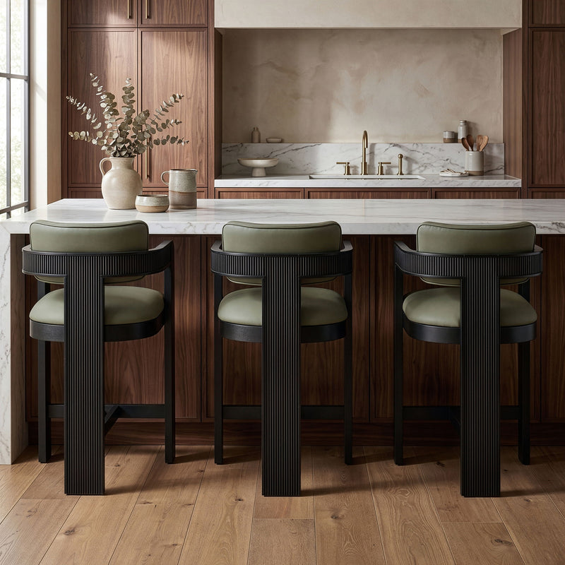 Set of 3 vegan leather counter stools with light green upholstered seats and black ribbed bases