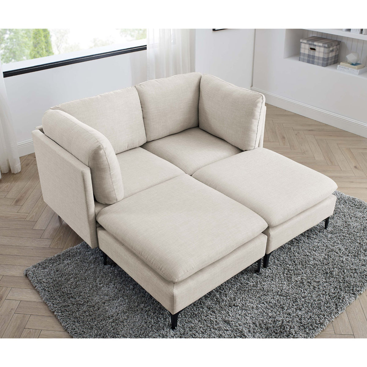 Beige sectional chaise sofa with tall black legs and gray area rug
