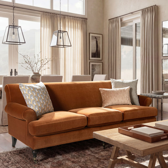 Modern three-cushion tightback sofa in warm orange fabric, with three accent pillows