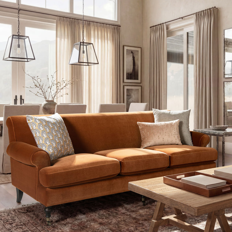 Modern three-cushion tightback sofa in warm orange fabric, with three accent pillows