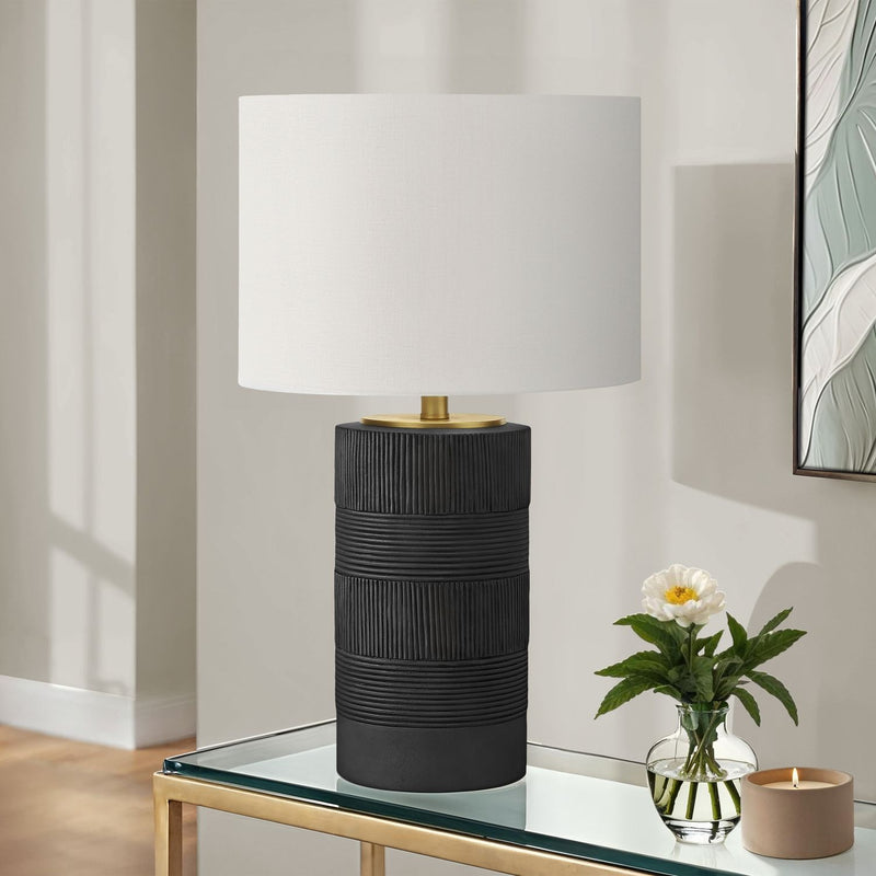 Resin table lamp with black ribbed base, cream fabric shade, and brass stem