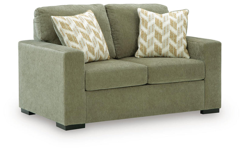 Green fabric loveseat with two geometric throw pillows and squared arms