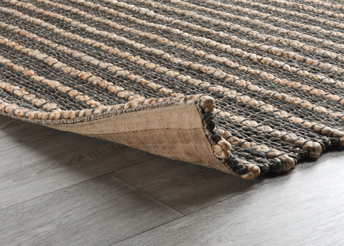 Corner detail of a striped natural fiber rug with woven texture and bound edge