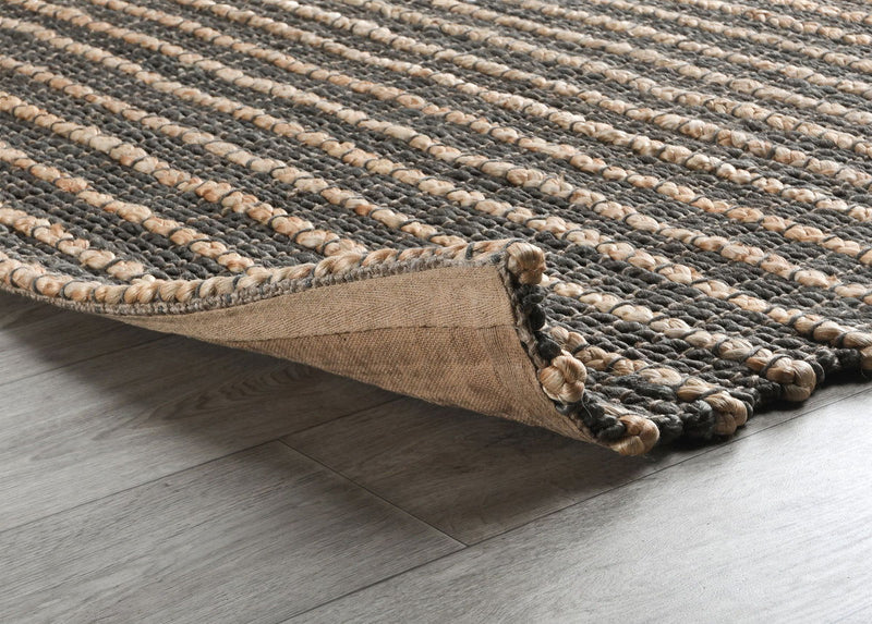Corner detail of a striped natural fiber rug with woven texture and bound edge