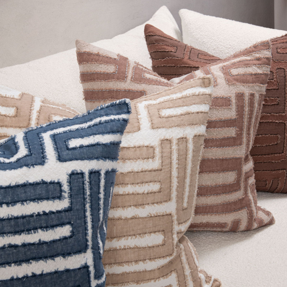 Decorative pillows with geometric maze patterns in blue, tan, and brown