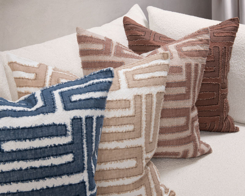 Decorative pillows with geometric maze patterns in blue, tan, and brown