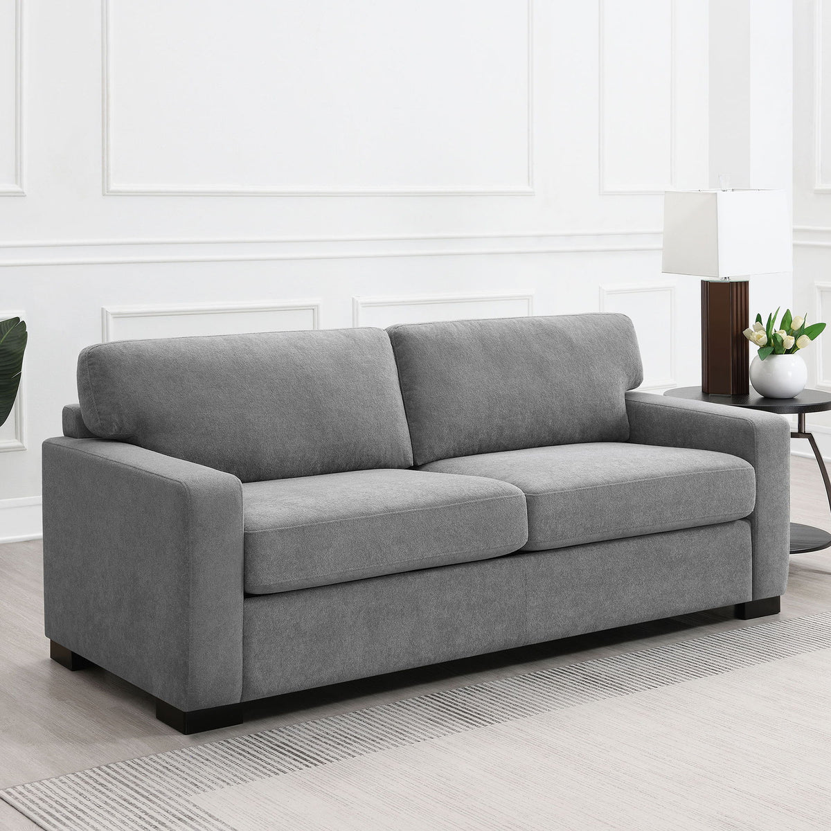 Gray fabric sleeper sofa with plush back cushions, rolled arms, and black feet