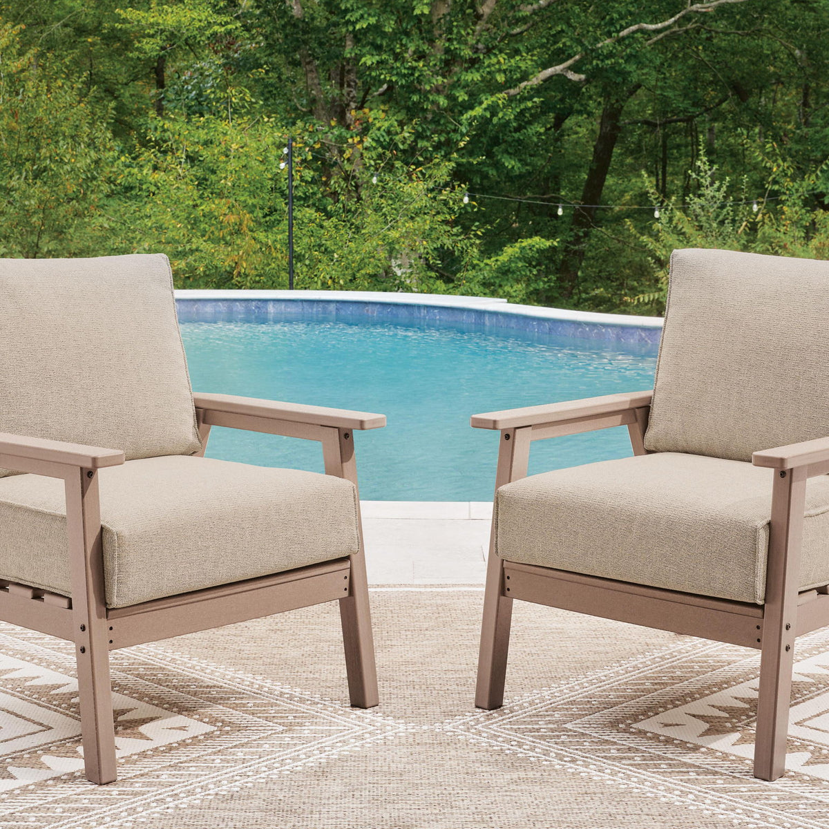 Two beige lounge chairs with fabric cushions and driftwood frames on outdoor patio