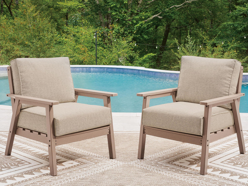 Two beige lounge chairs with fabric cushions and driftwood frames on outdoor patio