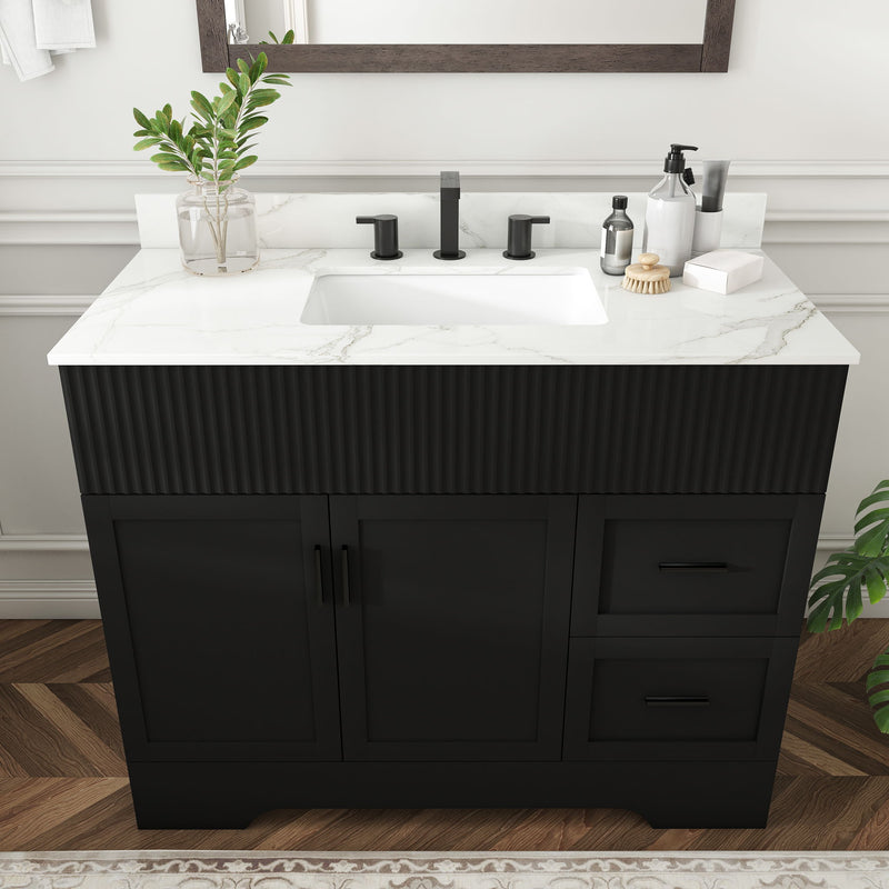 Black bathroom vanity with white countertop sink, three faucet holes, fluted cabinet