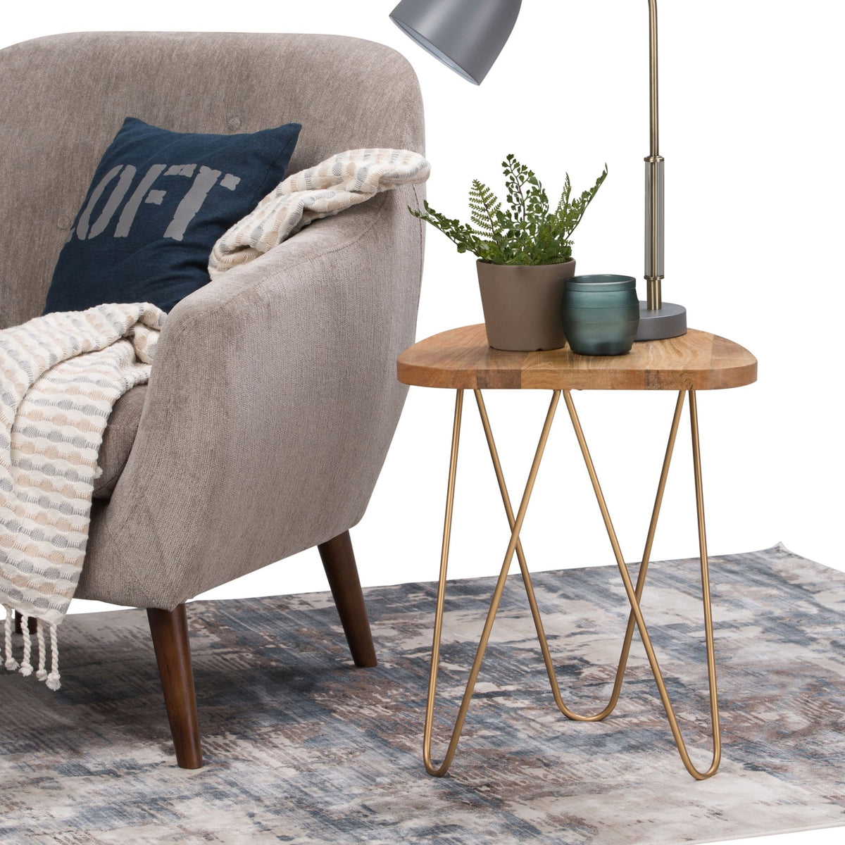 Round wood side table with gold hairpin legs next to a sofa and lamp