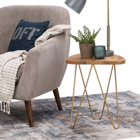 Round wood side table with gold hairpin legs next to a sofa and lamp