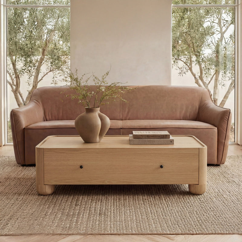 Natural wood coffee table with drawer, placed in front of sofa