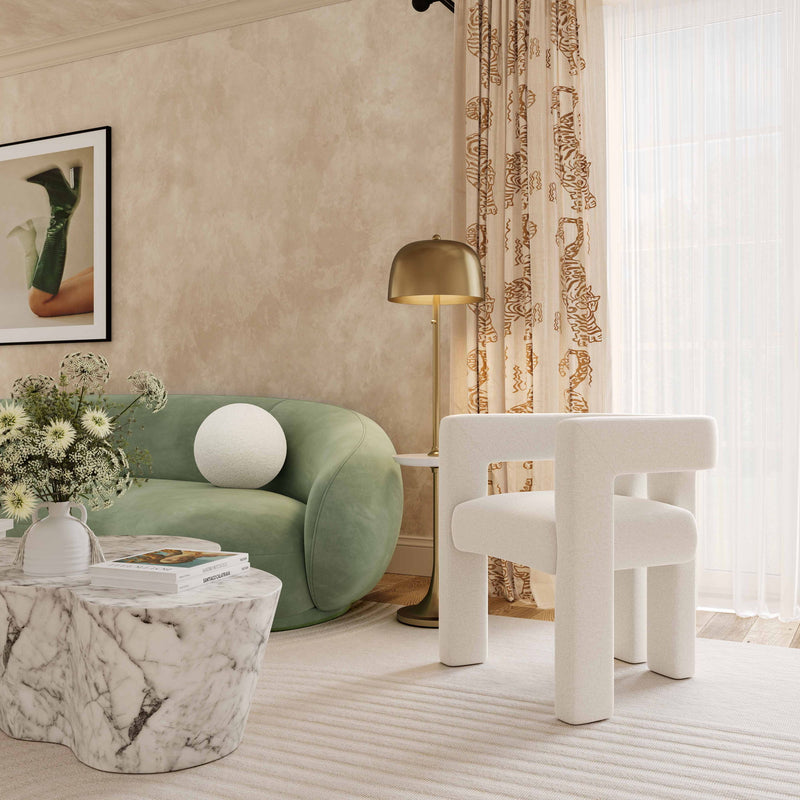 Beige round vegan shearling pillow on green couch, staged in room