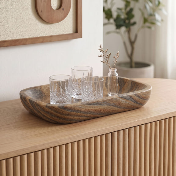 Sandstone oval tray holding glassware, showing swirling tan and gray stone pattern
