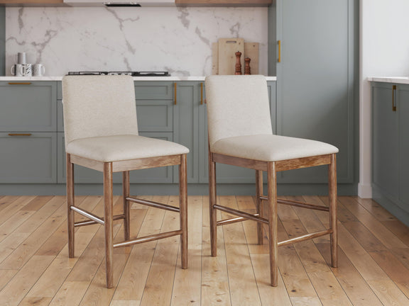 Two beige upholstered barstools with light brown wooden legs and built-in footrests