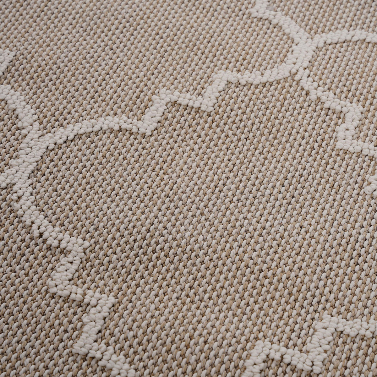 Beige textured rug surface with raised trellis pattern in a soft loop weave.