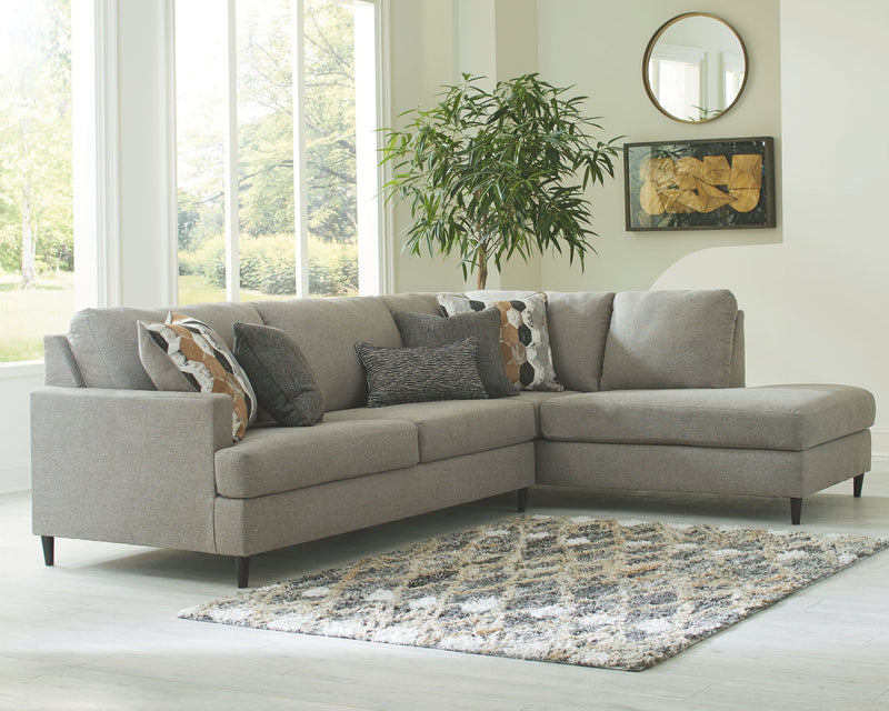Gray sectional sofa with chaise armrest and decorative pillows on cushions.