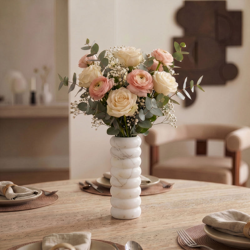 White marble vase with bouquet of flowers centerpiece on a dining table