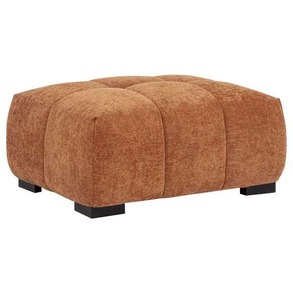 Light brown rectangular upholstered ottoman with tufted sections and low black legs.
