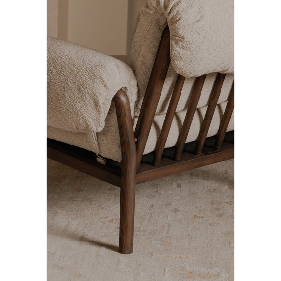 Close-up beige upholstered lounge chair arm and backrest with dark wood legs