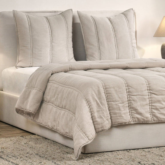 Quilt in light taupe with channel quilting, folded over bed blanket