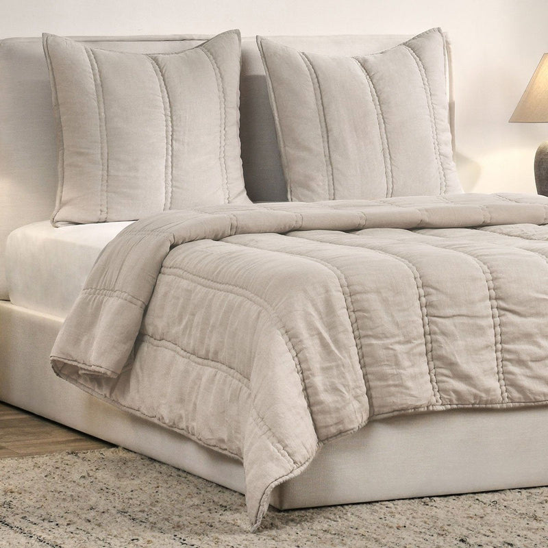 Quilt in light taupe with channel quilting, folded over bed blanket