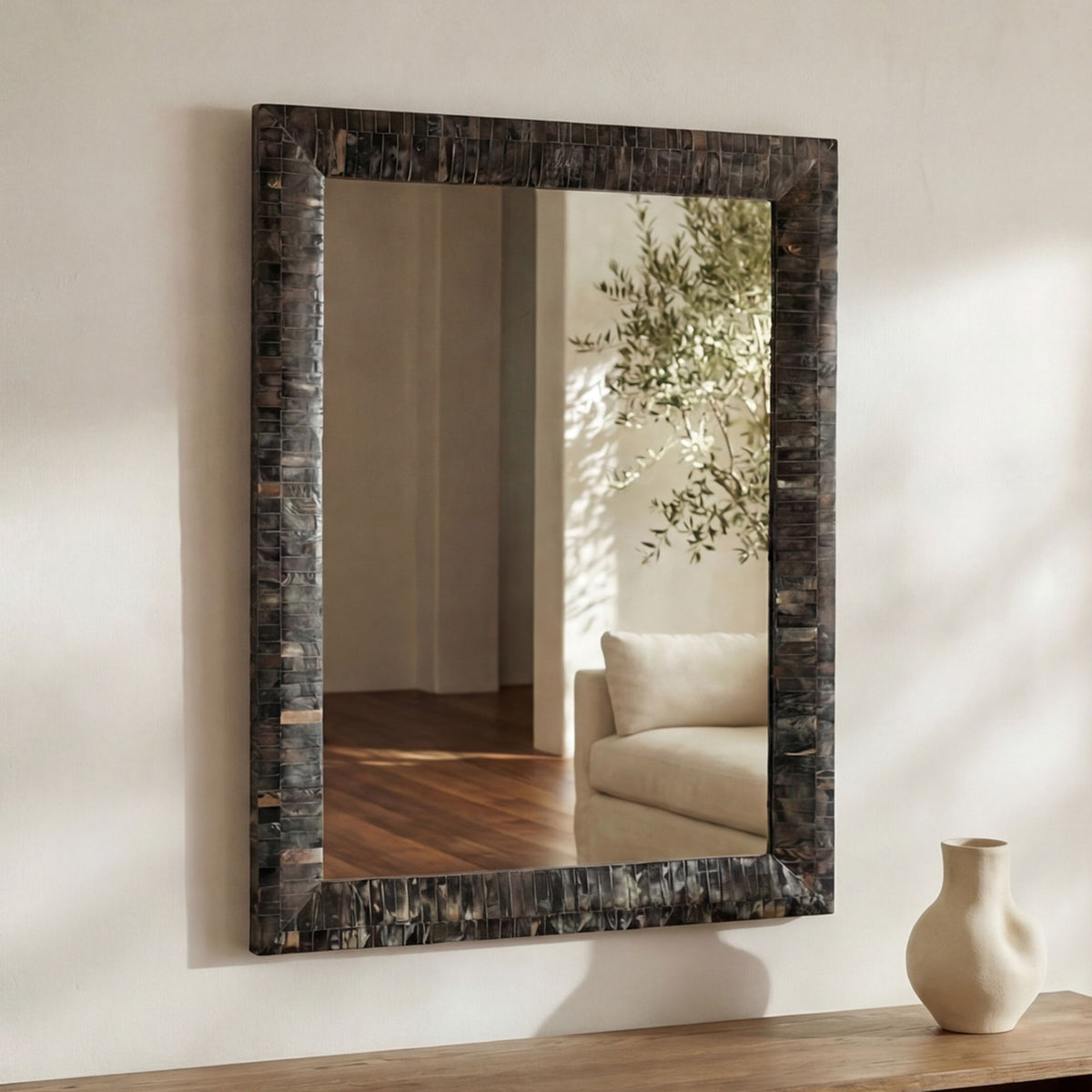 Wall mirror with horn inlay frame and multicolor border, reflecting interior seating