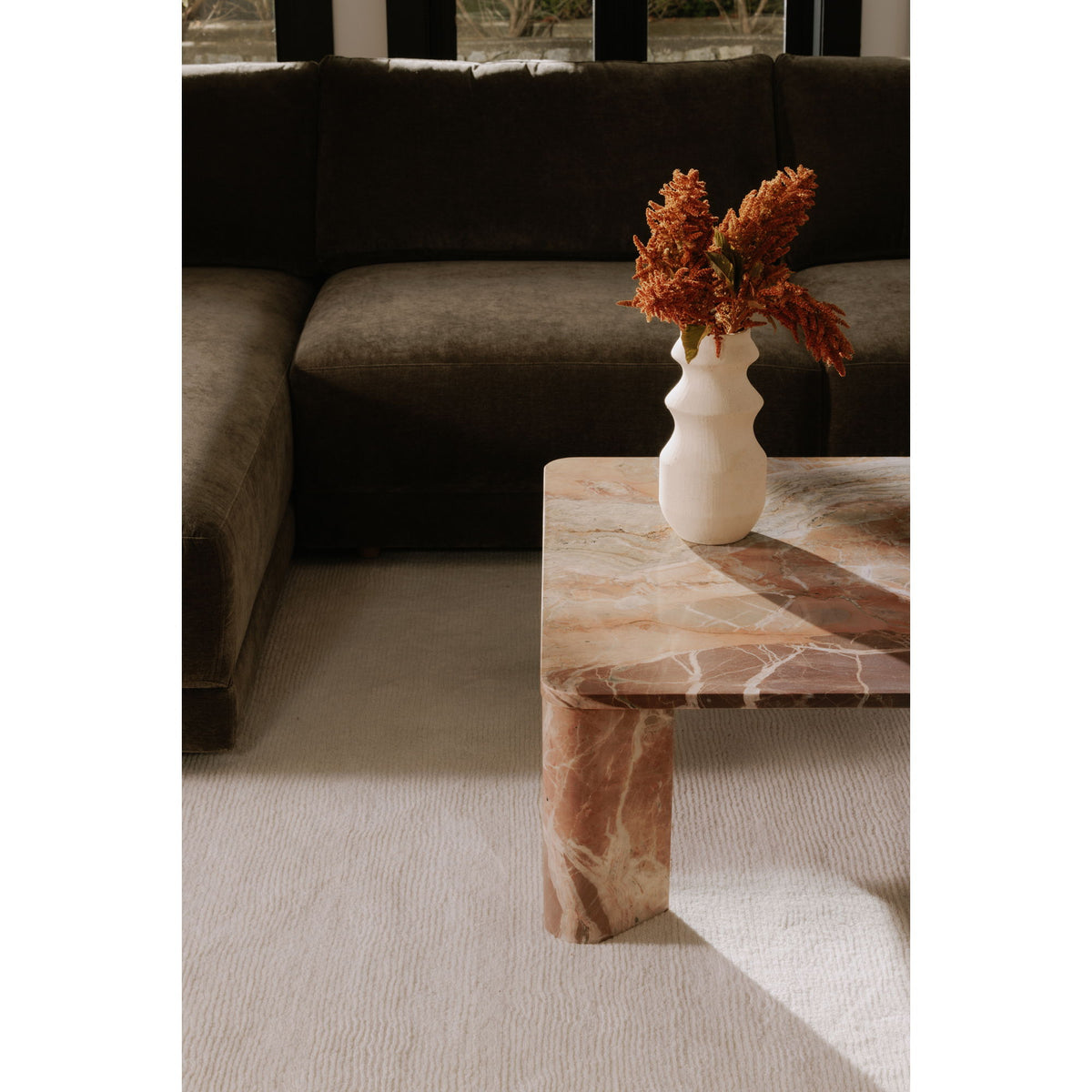 Orange marble coffee table with veined top, sculpted legs, vase on tabletop