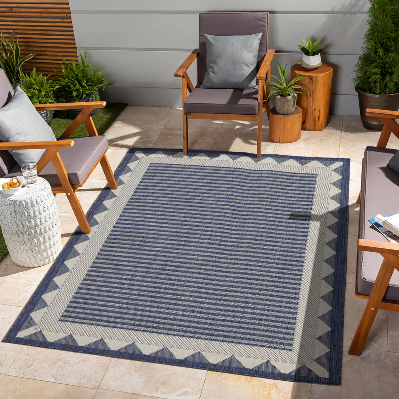 Blue outdoor area rug with fine striped pattern and cream zigzag border