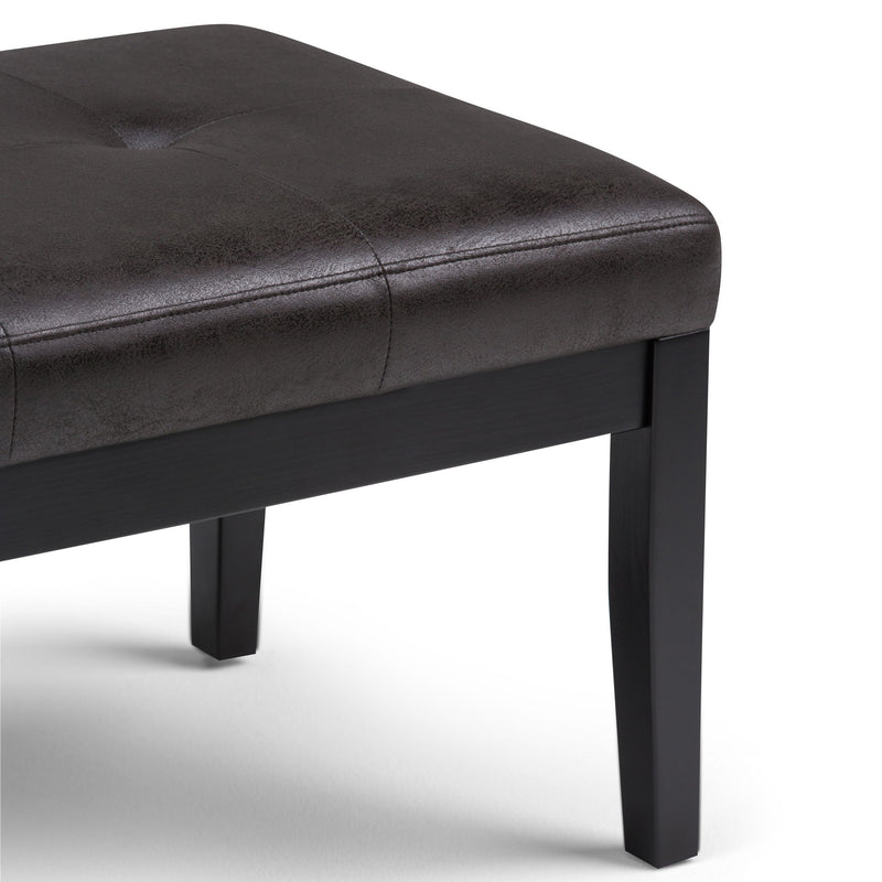 Tufted ottoman bench corner view, dark upholstery with stitched top seams