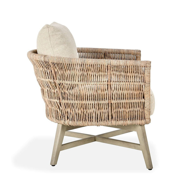 Outdoor accent chair side view with woven rattan arms and sand seat cushion