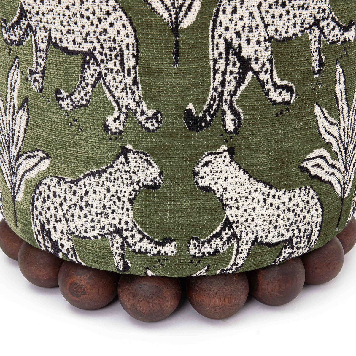 Close-up of dark green ottoman fabric with white animal pattern and dark wood ball base.