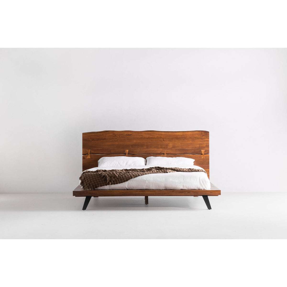 King platform bed with light brown wood headboard, white duvet, dark angled legs