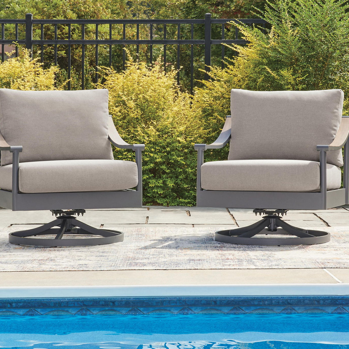 Two gray swivel lounge chairs with light cushions on patio near pool