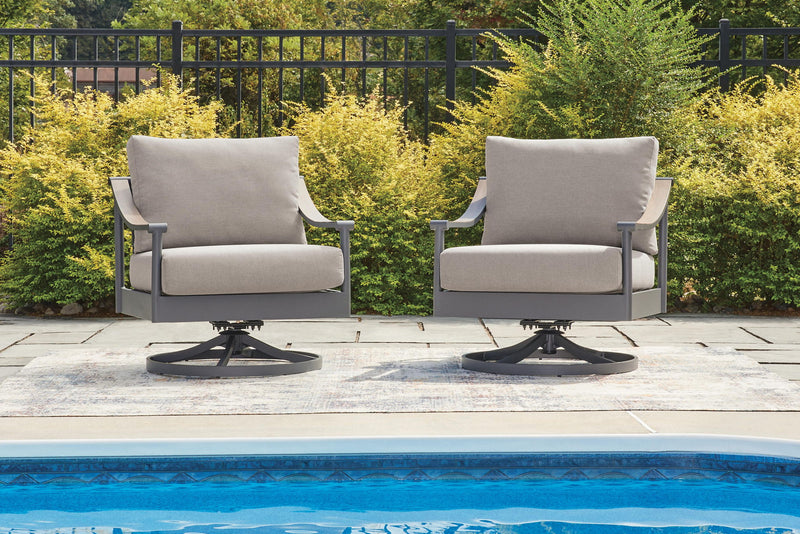 Two gray swivel lounge chairs with light cushions on patio near pool