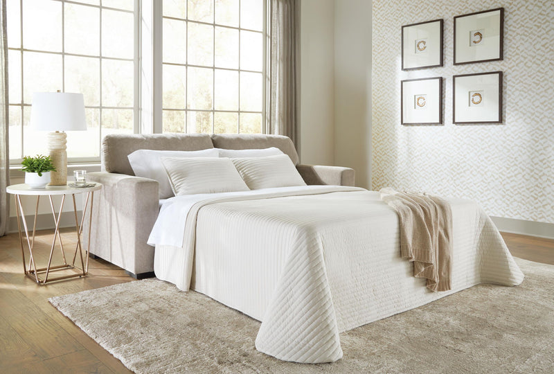 Beige sofa sleeper opened into a bed with white bedding and throw blanket